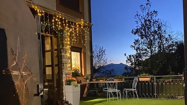 Een huis met een verzorgd gazon, een terras en sfeerverlichting.