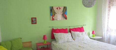 A bedroom with a bed, a nightstand, a lamp, and a painting on the wall.