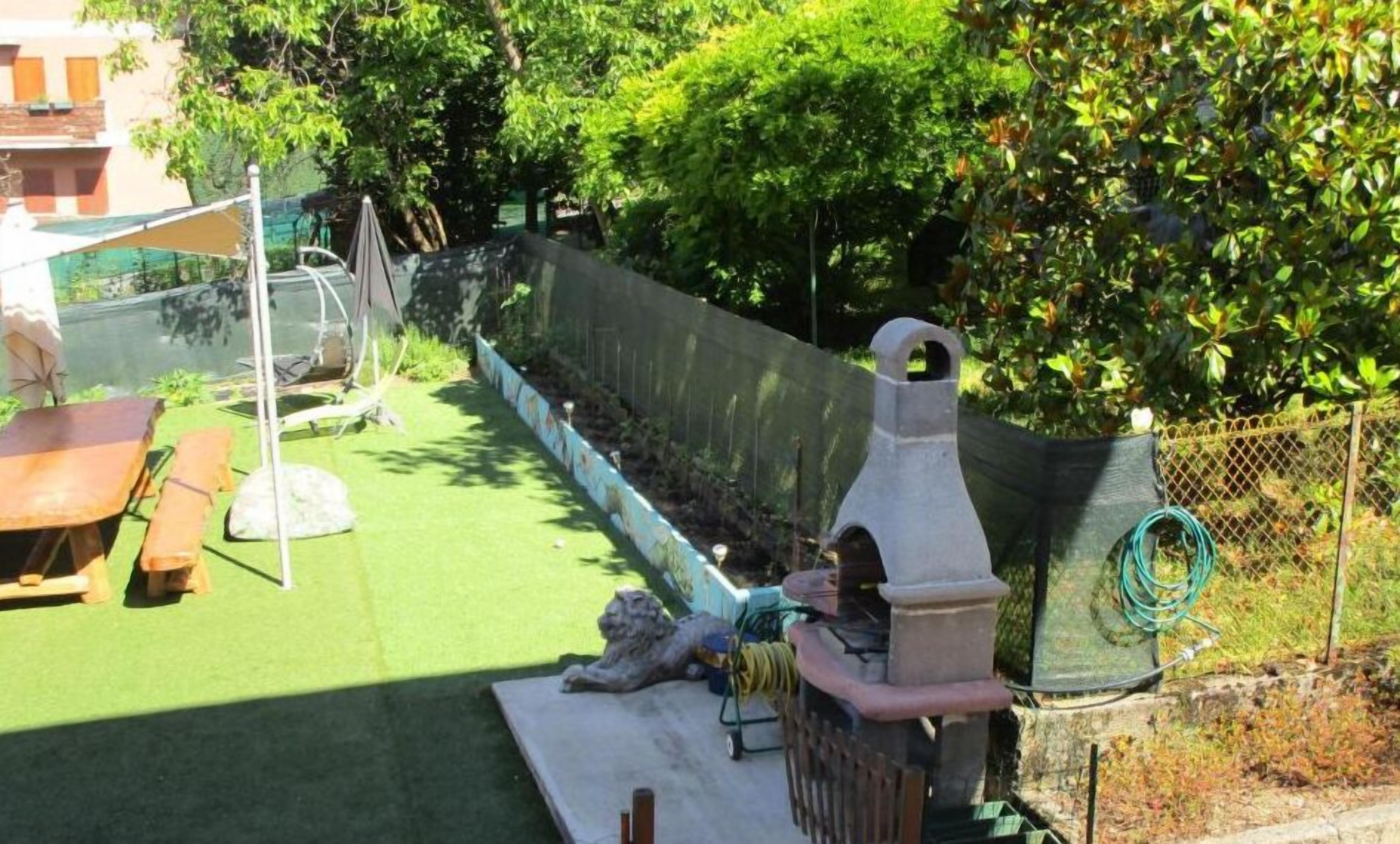 Eine Terrasse mit Grill, Gartenmöbeln und grüner Kunstrasen.