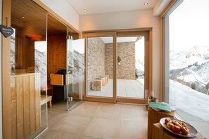 Un interno moderno con una reception in legno, un divisorio in vetro e vista su un paesaggio montano innevato.