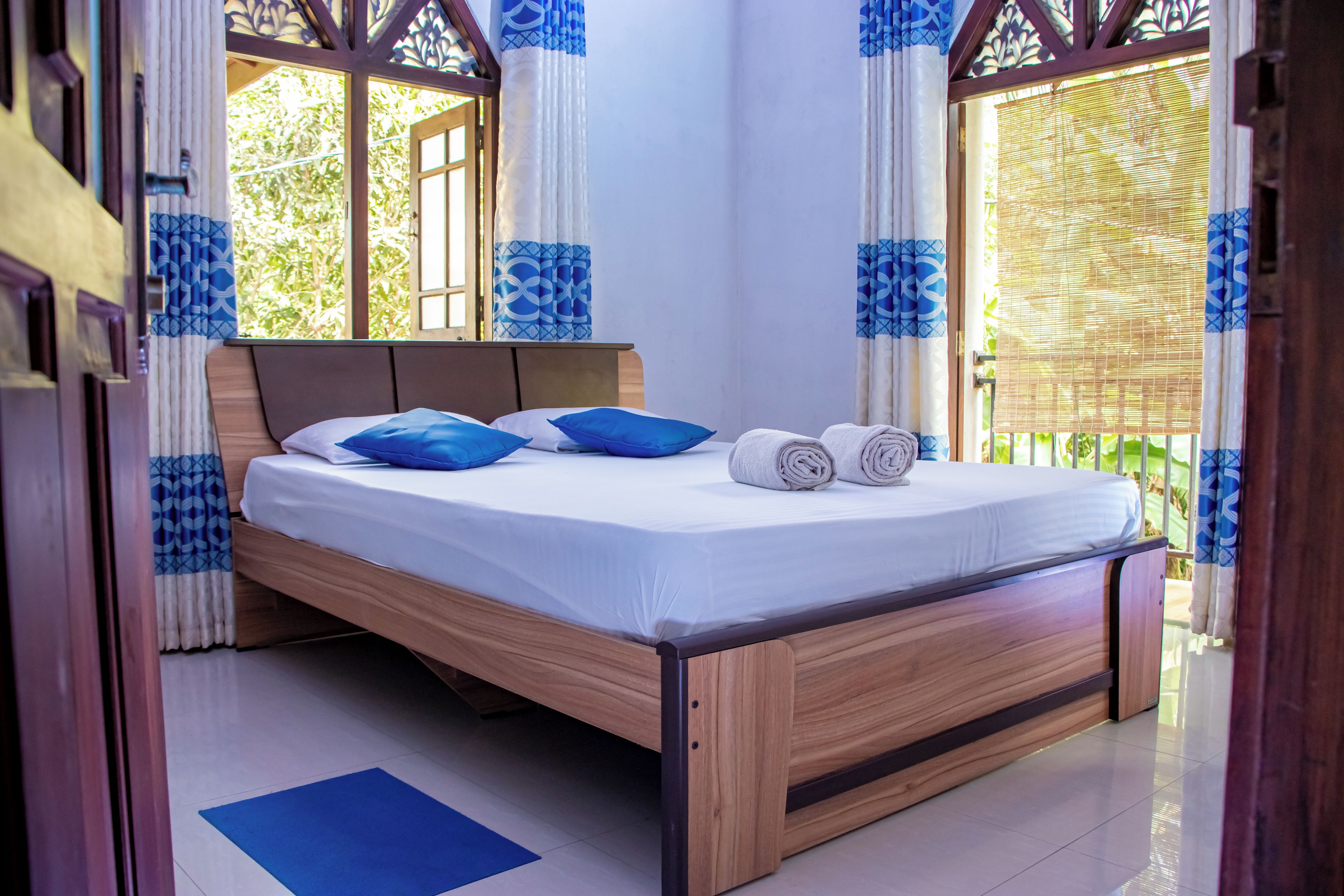 Una cama con estructura de madera, ropa de cama blanca y almohadas azules.