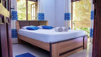 Una cama con estructura de madera, ropa de cama blanca y almohadas azules.