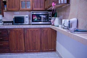 A kitchen with wooden cabinets, a microwave, a toaster, and a coffee maker. - DiNi Galle (Galle)