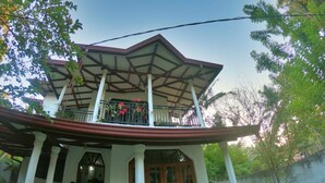 Une maison traditionnelle dotée d’un balcon, de piliers en bois et d’un toit recouvert de tuiles.