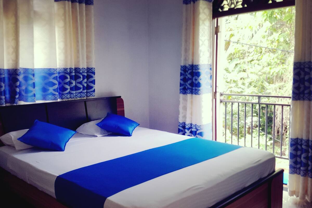A bed with blue and white bedding, a headboard, and curtains with a blue pattern.