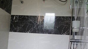 A bathroom with a white sink, black and white tiled walls, and a shower with a glass enclosure. - DiNi Galle (Galle)