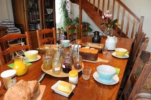 Une table à manger dressée avec divers aliments, notamment du pain, du beurre et des condiments.