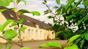 Un edifici amb teulada inclinada i un jardí amb vegetació verda.