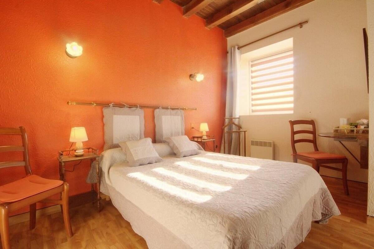 Un dormitorio con una cama grande, dos mesitas de noche con lámparas, una silla y una ventana con persianas.