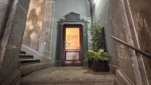 A staircase leading to a door with a sign, flanked by columns and a plant. - La Bella Napoli B&B (Naples)
