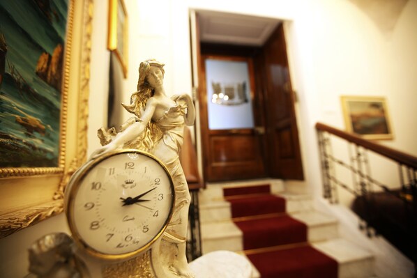 A staircase with red carpet and a clock with a statue on the wall.