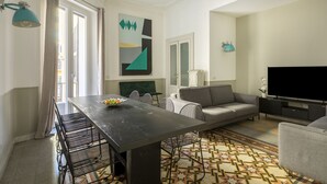 A modern living room with a dining table, grey sofa, and a flat-screen TV. - ROMAC - Mazzini (Rome)