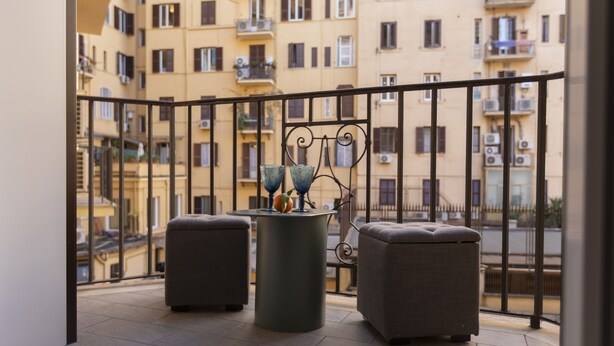 A balcony with two grey ottomans and a round table with decorative vases. - ROMAC - Mazzini (Rome)