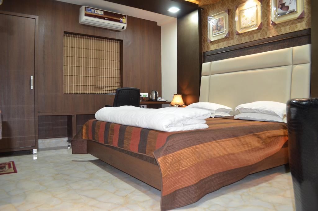 Een hotelkamer met een groot bed, een bureau, een stoel en een lamp.