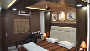 Habitación de hotel con cama, escritorio, silla y aire acondicionado instalado en la pared.