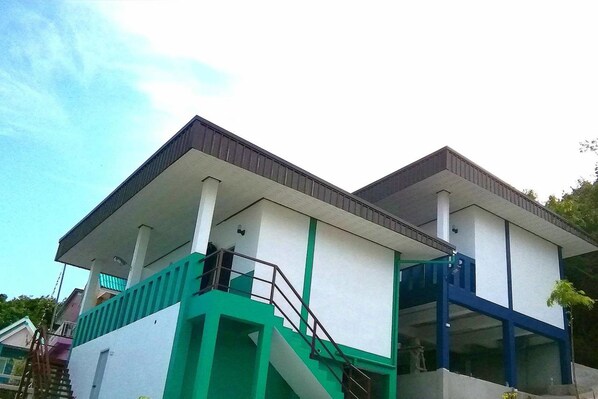 A two-story building with a flat roof, white walls, and green accents.
