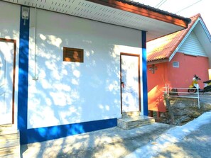 A building with a white exterior and blue trim, a red roof, and a small porch with steps.