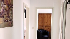 A hallway with wooden flooring, a black leather sofa, and a wooden door. - Pension Alabama (Lutherstadt Wittenberg)