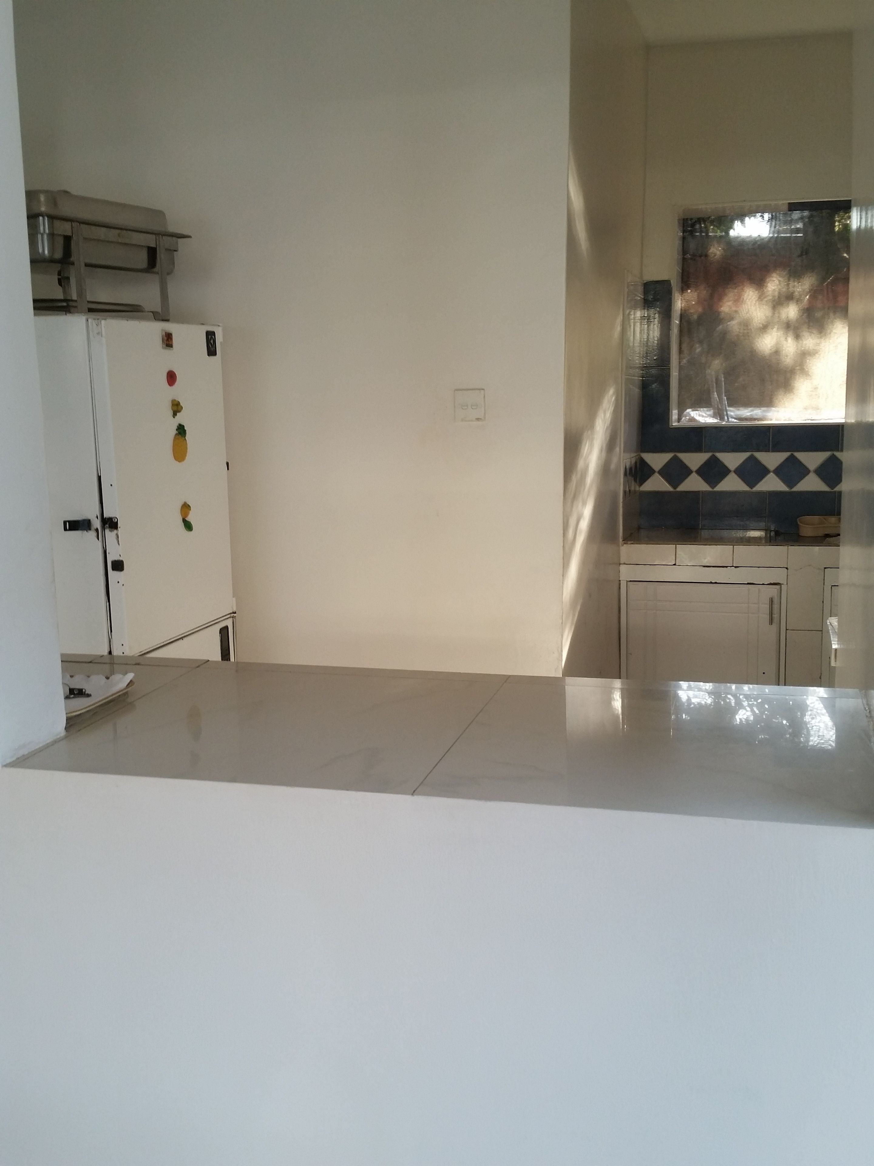 A kitchen with white cabinets, a stainless steel refrigerator, and a window with a view of trees.