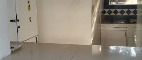 A kitchen with white cabinets, a stainless steel refrigerator, and a window with a view of trees.