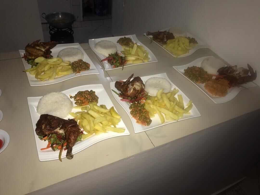 A table with multiple plates of food, including rice, fried chicken, and fries.