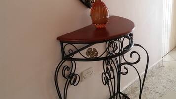 A corner with a decorative mirror, a small table with a vase, and a tiled floor.