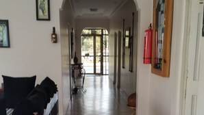 A spacious hallway with a bed, a fire extinguisher, and a door leading to another room. - Raha Leo Inn (Arusha)