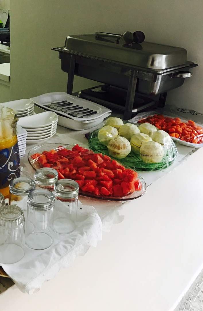 A buffet table with various food items, including sliced vegetables and a covered grill.