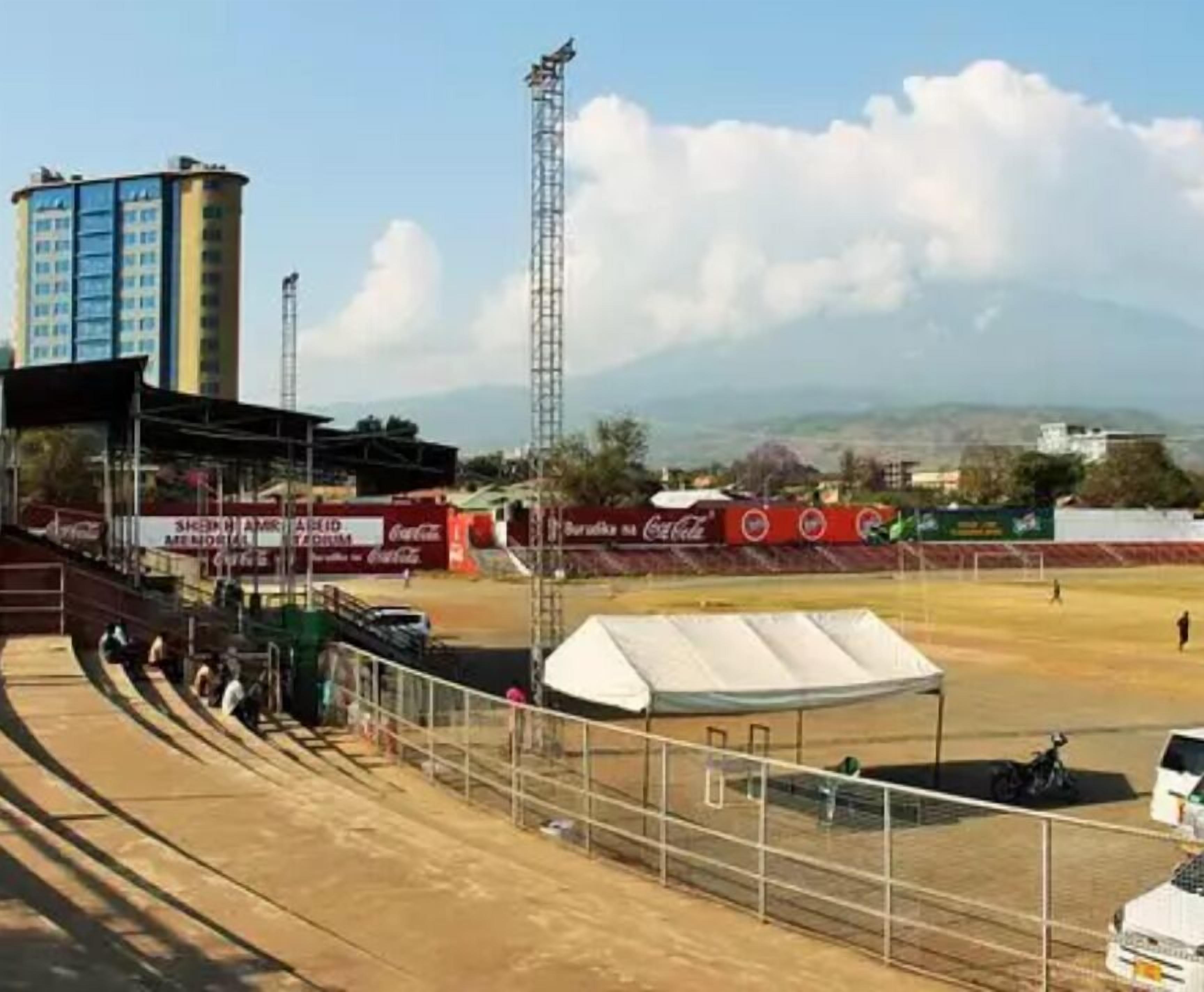 A stadium with tiered seating, a tall light tower, and Coca-Cola advertisements.