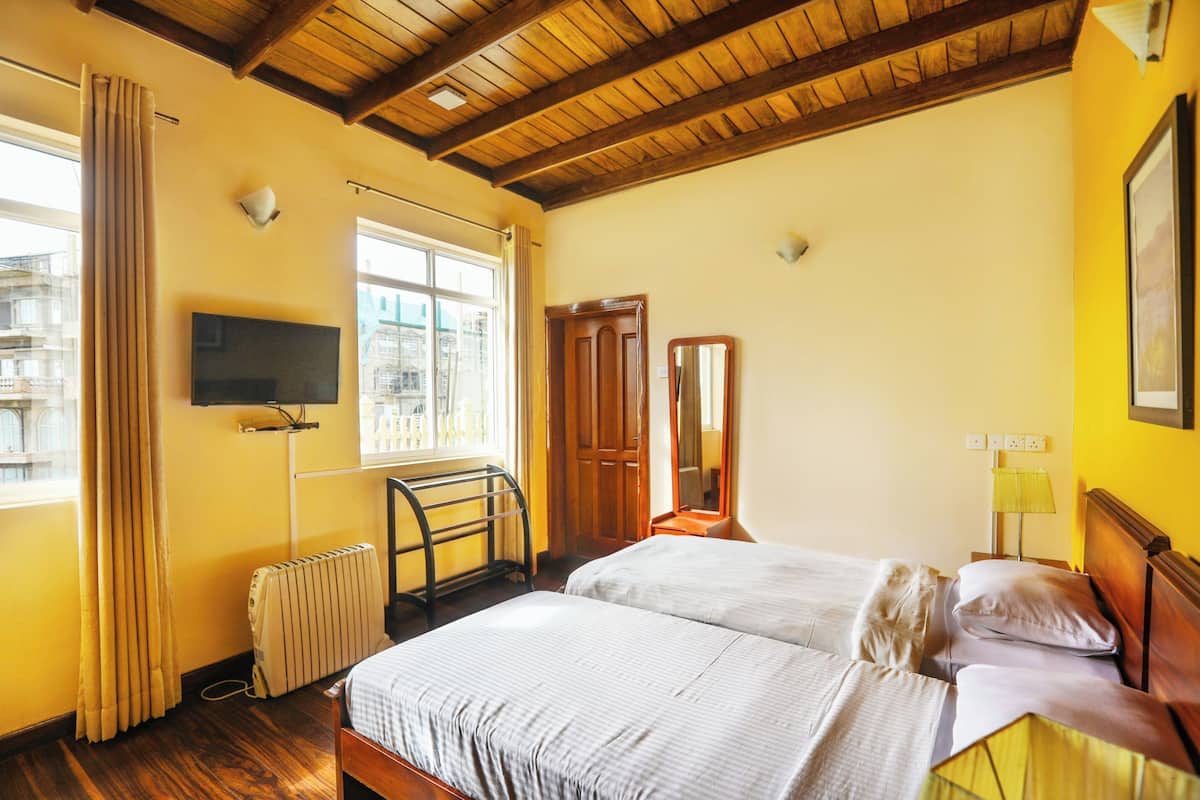 Ein Zimmer mit einem Bett, einem Fernseher, einer Heizung und einem Fenster mit Vorhängen.