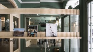 A modern interior with wooden shelves displaying magazines and a tripod. - Alda Jolio Jaca (Jaca)
