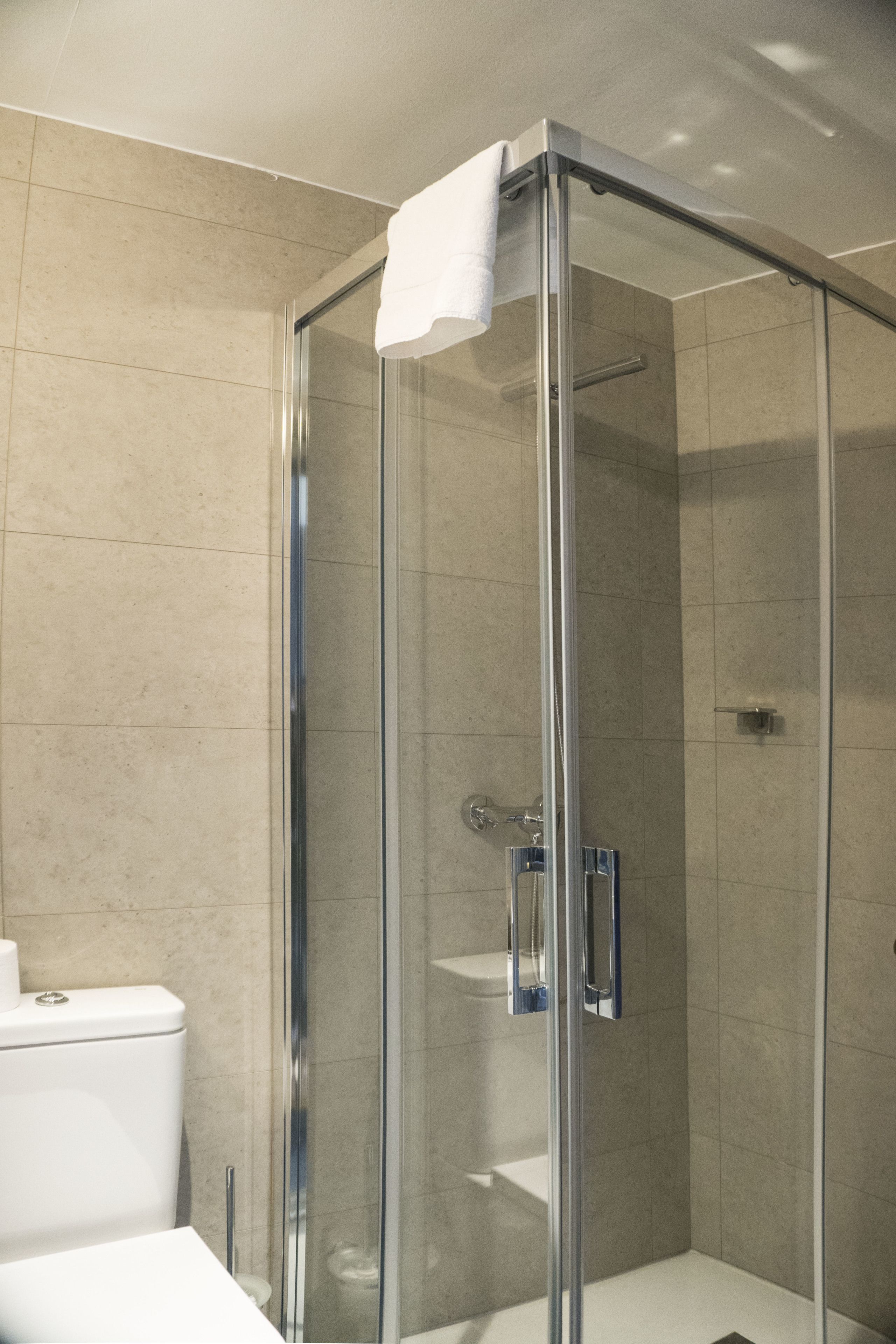 Uma casa de banho moderna com chuveiro envolto em vidro, sanita branca e lavatório.