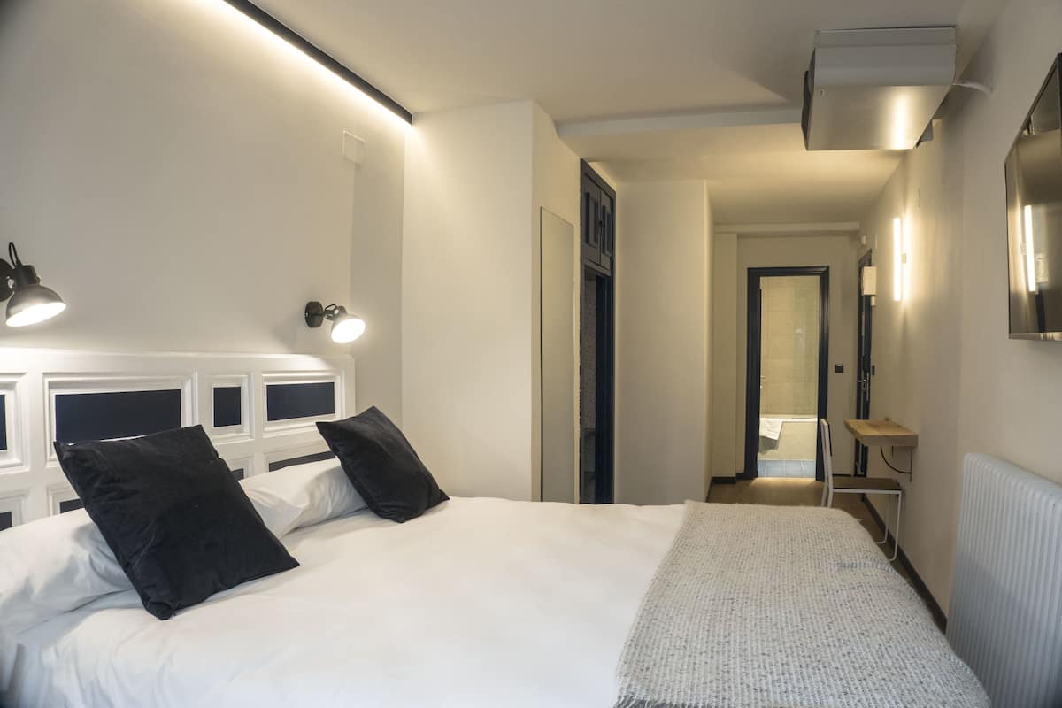 Una habitación de hotel con una cama grande, una mesita de noche, un espejo y un radiador.