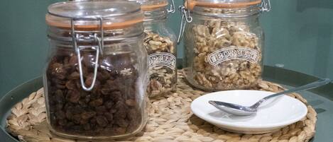 A table with three glass jars containing different food items, a plate with a spoon, and a woven placemat.