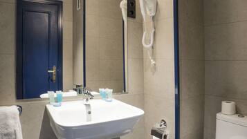 A bathroom with a white sink, a blue door, and a hairdryer mounted on the wall.