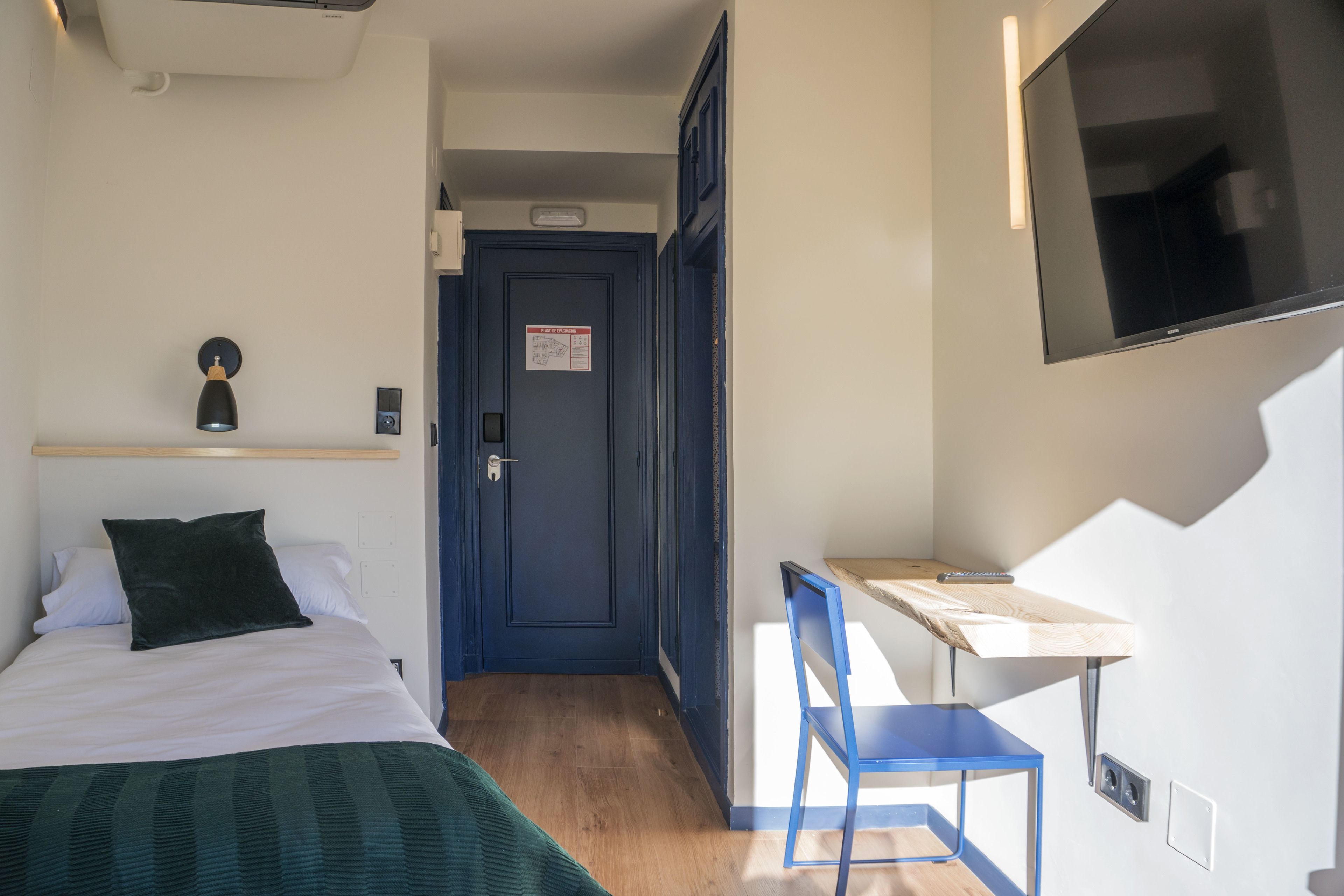 A hotel room with a bed, a desk, and a TV.