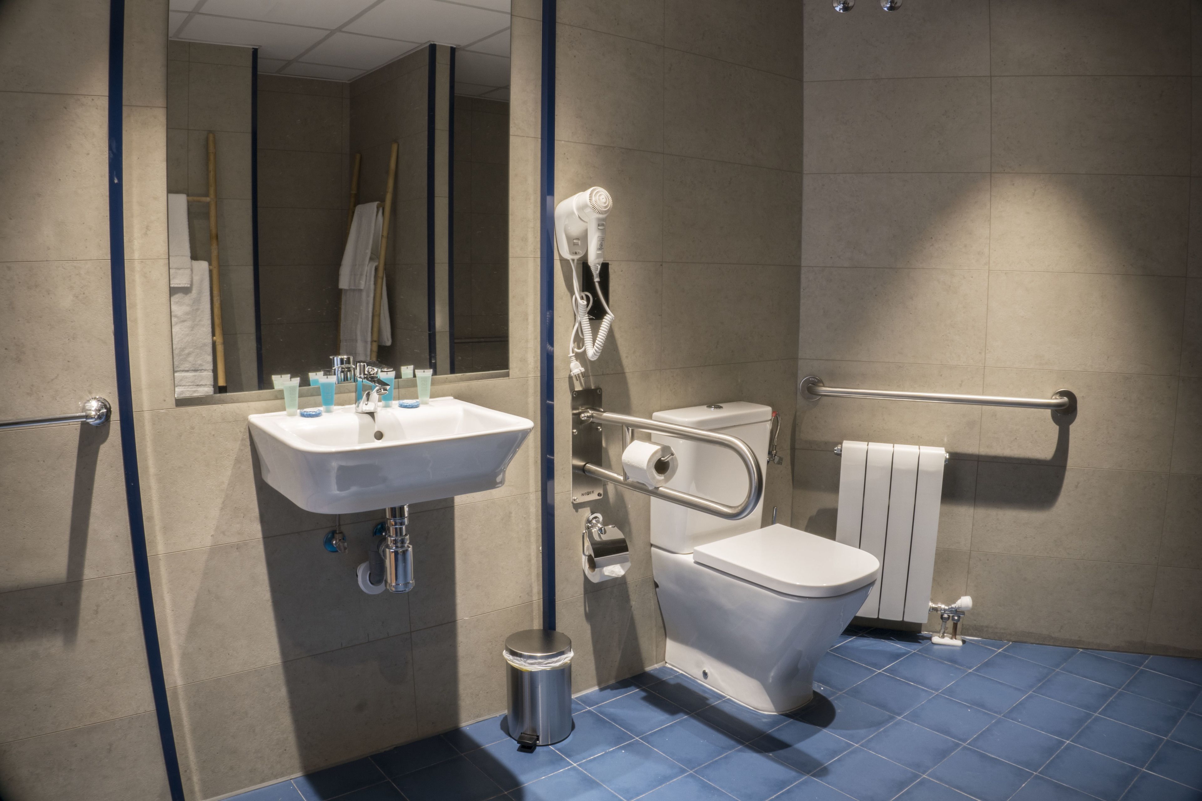 Une salle de bain moderne équipée d’un lavabo, de toilettes et d’un sèche-mains.