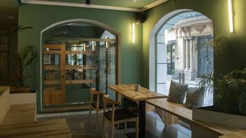 Un café acogedor con muebles de madera, puerta de cristal y paredes verdes.