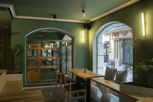 Un café acogedor con muebles de madera, puerta de cristal y paredes verdes.