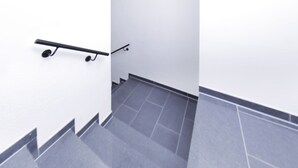 Una escalera con barandilla y piso de baldosas.