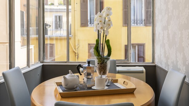 A round table with a tray containing a teapot, a cup, and a glass, a potted plant, and a coffee maker. - ROMAC - Condotti I (Rome)