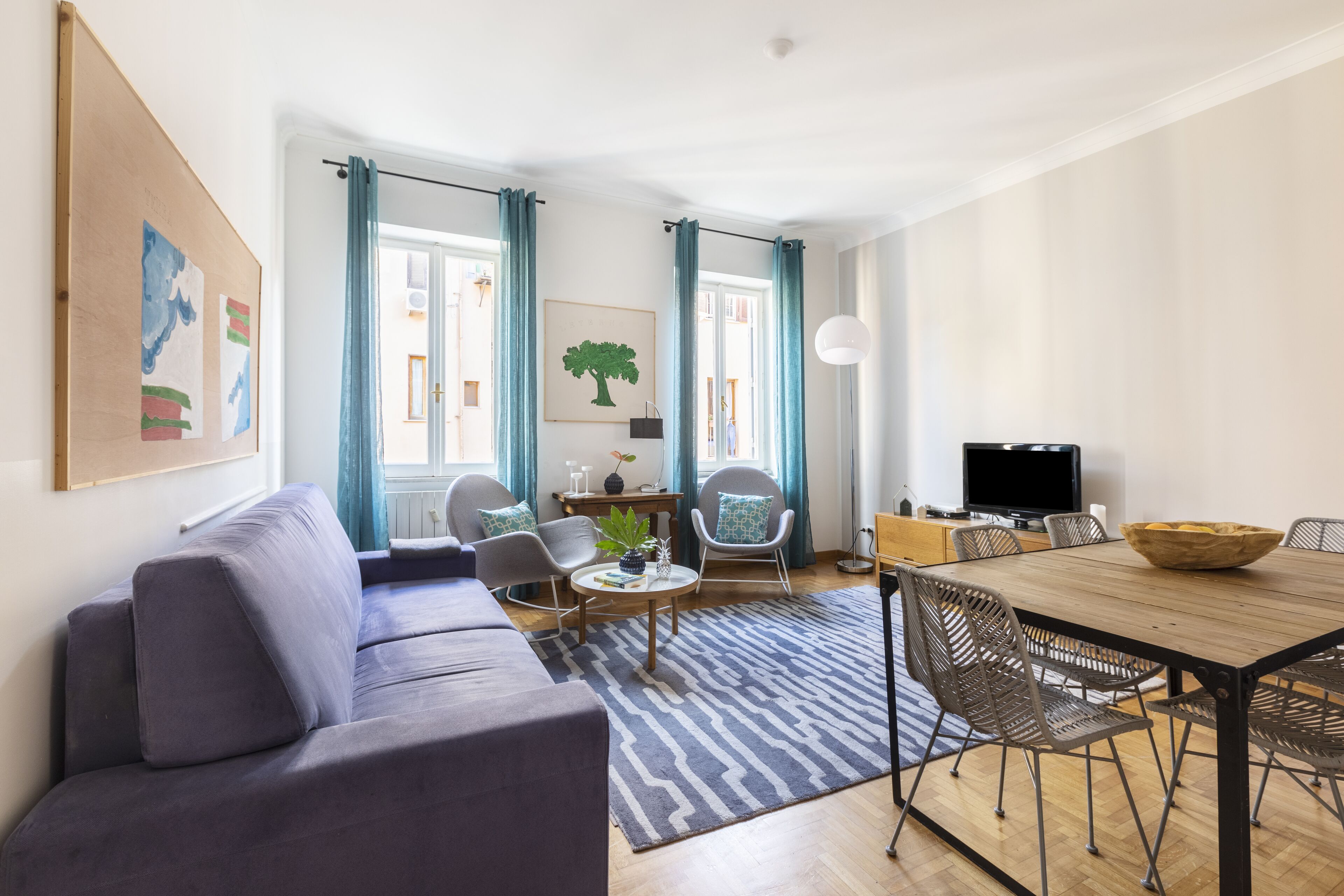 Een moderne woonkamer met een bank, stoelen, een salontafel en een eettafel met stoelen.