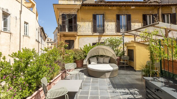 Un patio con una zona de estar circular al aire libre, una mesa y sillas.
