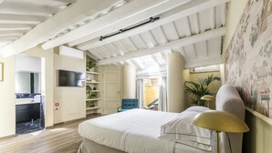 Un dormitorio con una cama grande, un televisor, una silla y un escritorio.
