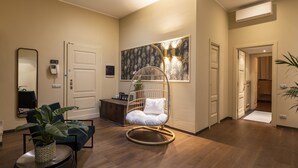 Una sala de estar moderna con piso de madera, un sillón colgante, una planta en maceta y un aire acondicionado instalado en la pared.