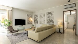 Una sala moderna con un sofá beige, un televisor de pantalla plana y arte abstracto en la pared.