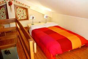 Un dormitorio con una cama de madera, dos lámparas de noche, una cortina con motivos florales y una escalera de madera.