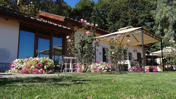 Una casa con un patio, una mesa y sillas. Hay flores y un jardín al frente.