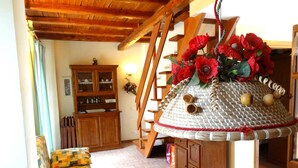 Un salón acogedor con un sofá estampado, un mueble de madera y una estructura decorativa tejida con flores rojas.