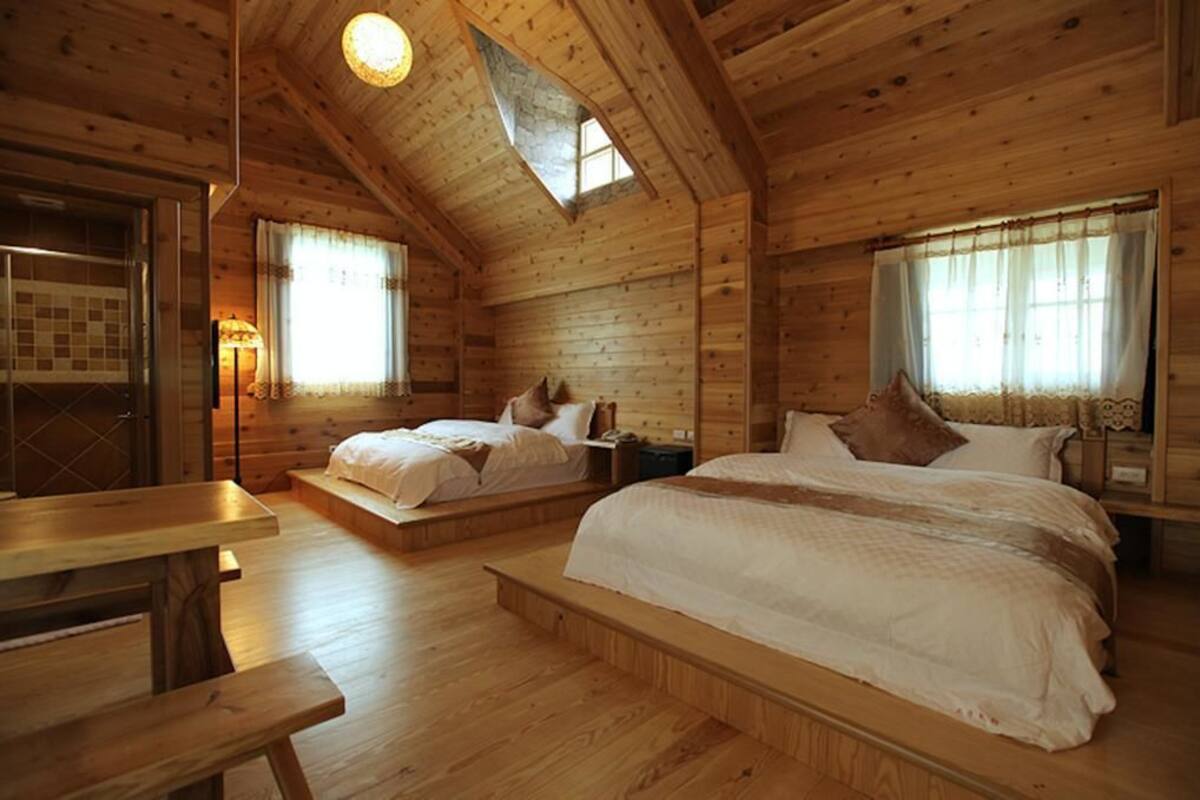 A cozy log cabin bedroom with two beds, a wooden table, and a skylight.